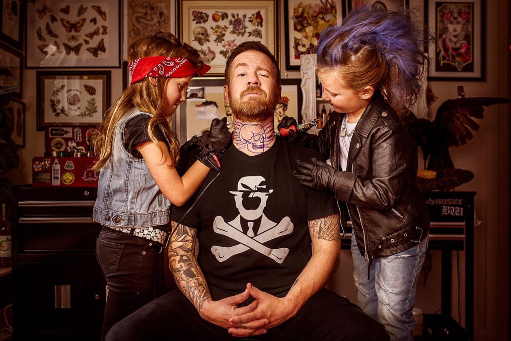 Professional portrait of Halifax artist Liam Hennessey as his daughter apply a tattoo